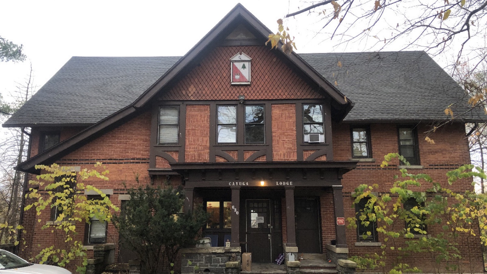 The front of the Lodge: a brick and timber house with the Cayuga Lodge crest over the porch